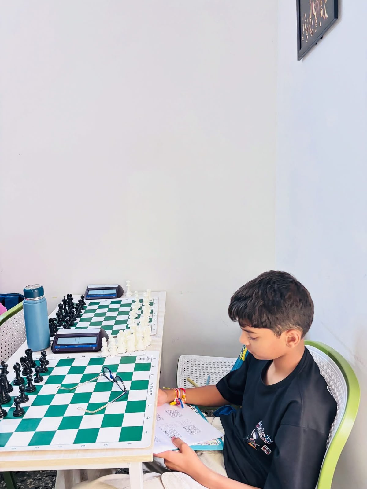 Student completing chess notation practice beside a tournament board