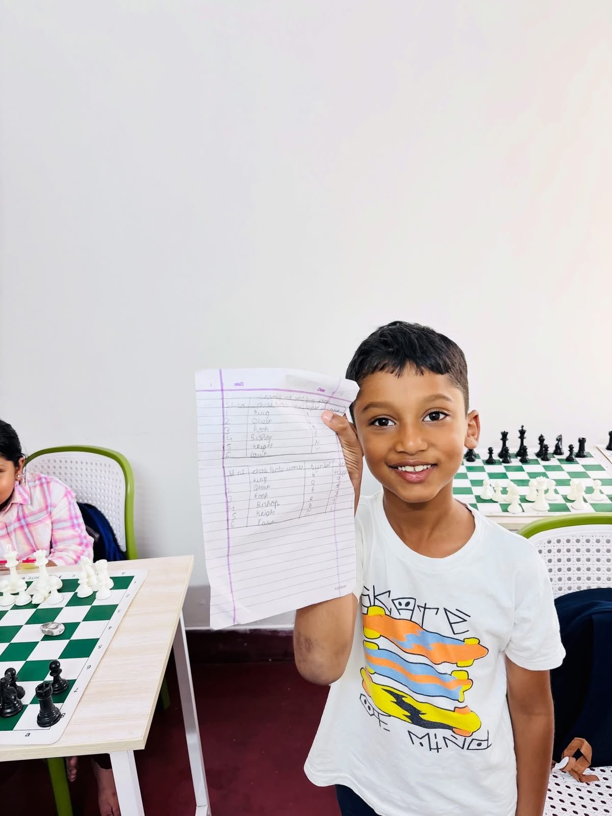 A student proudly displaying completed chess learning notes