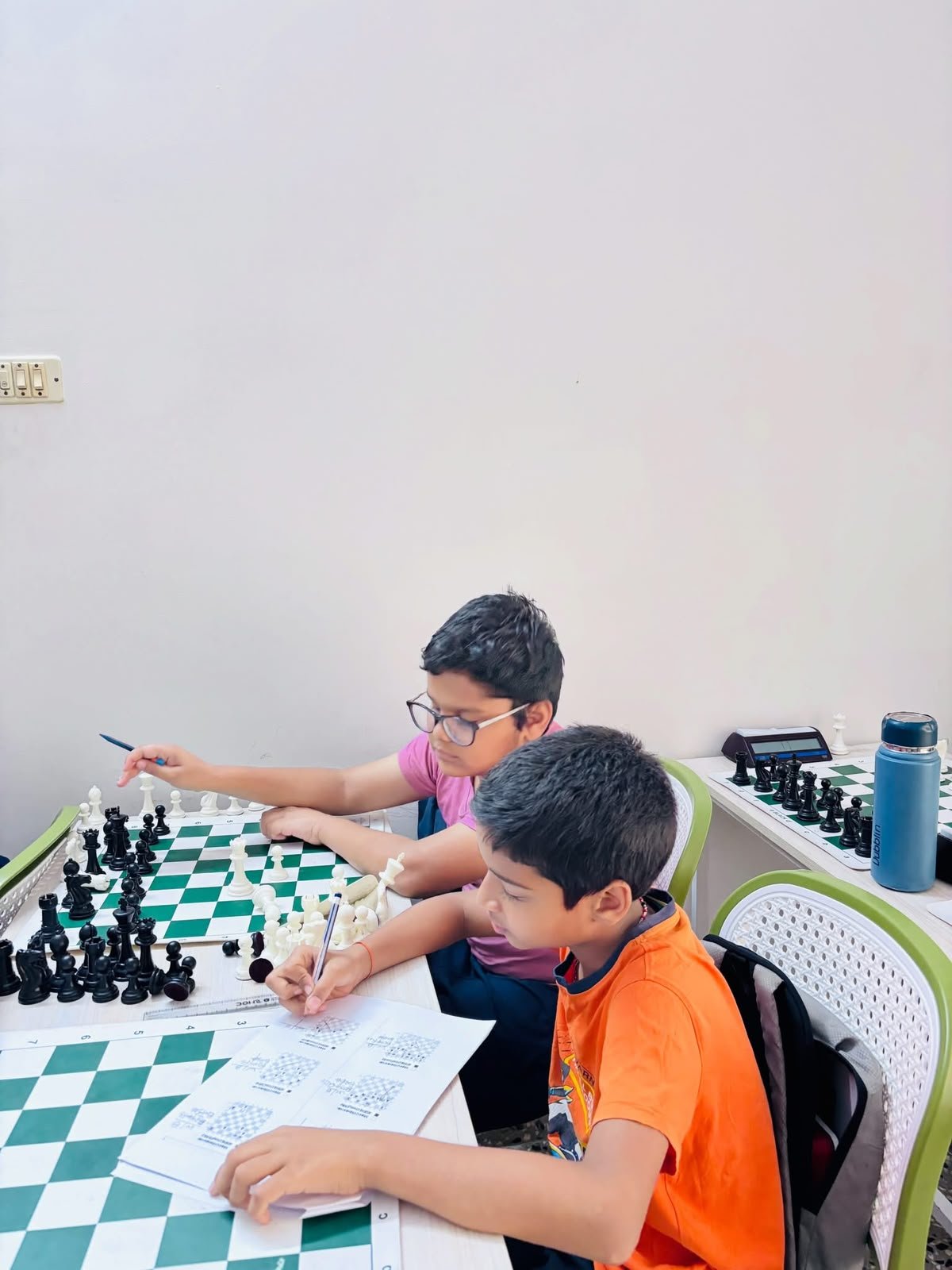 Young students solving chess exercises beside their boards